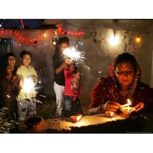 Woman Lights Earthen Lamps as Children Ignite Firecrackers in New 