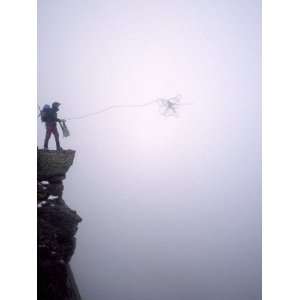  Man Throws His Climbing Rope Through the Fog Off a High 